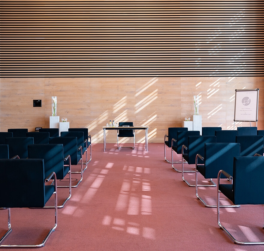 Ein Seminarraum im Tagungshotel am Tegernsee mit mehreren in Reihen angeordneten Stühlen und im Zentrum ein weiterer Stuhl mit Tisch für den Referenten.