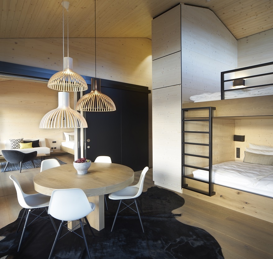 Aufnahme im Schlafraum des Alpenchalets am Tegernsee mit einem schwarzen Teppich, einem Esstisch und einem Alkoven-Bett.